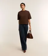 Blusa básica de mujer color negro, confeccionada en malla encorpada de algodón, con cuello redondo y mangas cortas de corte oversized con sisas desplazadas.