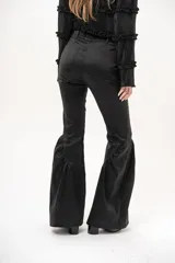 Pantalón negro de tiro medio, corte oxford, con bolsillos laterales y cierre frontal. Destaca por su diseño ajustado en la parte superior y volados fruncidos a partir de la rodilla que aportan volumen y movimiento.