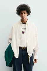 Camisa de corte relajado confeccionada en tejido con mezcla de lino. Presenta cuello solapa, manga larga con puños abotonados, bolsillo plastrón en el pecho y cierre frontal con botones. Incluye bordados a contraste en la espalda.
