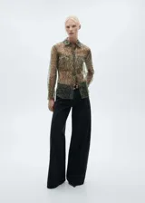 Camisa de organza semitransparente con estampado de serpiente en tonos marrones y verdes. Tiene corte recto, cuello camisero, dos bolsillos de parche en el frente y cierre de botones.