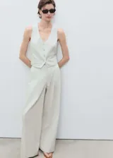 Pantalón de tiro medio con diseño recto y estilo sastrero. Confeccionado en tejido mezcla de algodón y lino con estampado de rayas verticales finas. Cuenta con cierre delantero de cremallera y botón, trabillas para cinturón y bolsillos laterales.
