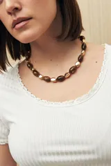 Collar corto con cuentas ovaladas color marrón combinadas con cuentas doradas.