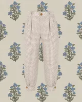 Bombacha de campo unisex confeccionada en algodón con estampado a cuadros vichy en tonos beige y blanco. Presenta cintura con trabillas, cierre frontal con botón, pinzas en la parte superior y puños ajustados en los tobillos con detalle de botón.