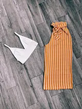 Pantalón palazzo color mostaza con rayas verticales blancas y lazo en la cintura.