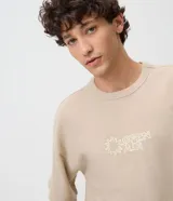 Remera de manga corta color beige, con cuello redondo y bordado frontal con motivo gráfico y texto 'Open Air'.