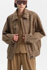 Chaqueta de lana y poliéster con diseño de pata de gallo en tonos marrones y verdes. Presenta cuello solapa, cierre frontal asimétrico con cremallera y botones, y puños con botón.