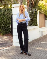 Botinetas tipo Chelsea de cuero negro, con paneles laterales elásticos y detalle de textura grabada en el talón. Presentan una suela plana con plataforma de madera clara y base de goma negra.