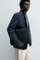 Maletín negro de acabado liso, con asa de mano y asa de hombro ajustable y extraíble. Presenta un compartimento principal con cierre de cremallera y un bolsillo frontal plano.