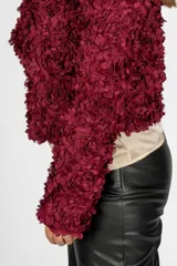 Bolero color bordó con textura de pétalos, mangas largas y corte a la cintura.