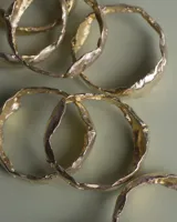 Brazalete rígido de diseño orgánico con textura irregular y acabado brillante, elaborado artesanalmente en metales nobles.