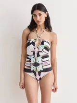 Malla entera con estampado abstracto en blanco, negro, verde, violeta y rosa. Diseño halter con escote en V y detalle de argolla en el centro del busto.