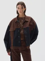 Campera tipo trucker de corte oversize, confeccionada en algodón con diseño colorblock en tonos azul marino y bordó. Presenta cierre frontal con botones metálicos, cuello clásico y bolsillos frontales con solapa.