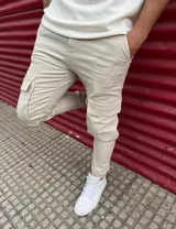 Pantalón cargo beige de corte chupín con bolsillos laterales XL en las piernas y puños elásticos en los tobillos.