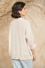 Campera color beige de lino, con cuello mao, mangas 3/4 con botón para sujetar, cierre frontal con botones y ajuste con cordón en la cintura.