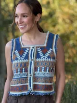 Chaleco corto en denim con bordado artesanal multicolor y escote cuadrado. Con cierre de botones y terminaciones desflecadas.
