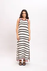 Vestido largo de punto con diseño de rayas en zigzag de color blanco y negro, sin mangas, con ribetes en tono bordó en el cuello y las sisas, y aberturas laterales en el bajo.