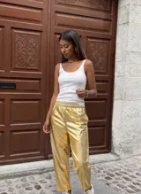 Pantalón dorado de calce relajado, cintura elástica, bolsillos delanteros y traseros, de textura suave y liviana.