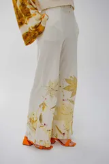 Pantalón de pierna ancha color crema con estampado de hojas amarillas.