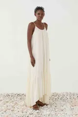 Vestido largo blanco de breteles finos con patrón de rayas sutiles, escote redondo y silueta fluida con volado en el ruedo.