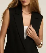 Chaleco negro de punto roma con escote blazer, cierre con dos botones y bolsillos delanteros.