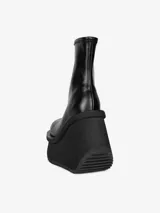 Bota negra de caña media con plataforma y cuña esculpida.