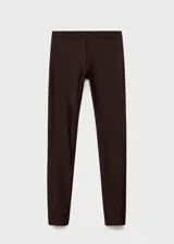 Pantalón slim fit de color marrón oscuro, con diseño largo, cintura elástica y detalle de costuras. Presenta una abertura en el bajo con cierre de cremallera.