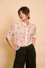 Camisa de seda color marfil con estampado floral pequeño, cuello mao y mangas cortas con presilla y botón para arremangar.
