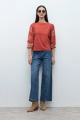 Remera de manga larga con cuerpo liso en color terracota y mangas abullonadas con estampado botánico en tonos tierra. Presenta cuello redondo y puños ajustados.