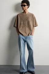 Remera relaxed fit color marrón con cuello redondo, manga corta y parche bordado a tono con letras en el frente.