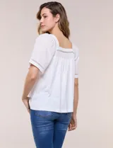 Blusa de corte holgado color marfil, confeccionada en mezcla de modal y algodón, con escote cuadrado y mangas cortas adornadas con detalles de puntilla calada.
