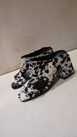Sandalias de tacón con estampado de vaca en blanco y negro, confeccionadas en piel con acabado de pelo, diseño destalonado de punta abierta y taco ancho.