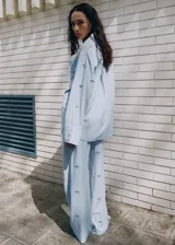 Pantalón largo de popelín celeste con estampado de rayas verticales, cintura elástica ajustable y detalles de lentejuelas brillantes.
