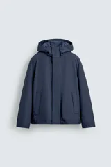 Parka de tejido técnico con acabado engomado, cuello subido y capucha ajustable. Presenta cierre frontal con cremallera oculta bajo solapa con botones a presión, bolsillos laterales de vivo y mangas largas con puños ajustables.