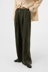 Pantalon de lino verde militar, de calce relajado y pierna amplia, con cintura elastizada, boton delantero y pinzas en el frente.