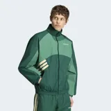 Campera deportiva Adidas Múnich 93 en tonos de verde, con cuello alto, cierre frontal y las icónicas tres tiras en las mangas. Diseño holgado con detalles en contraste.