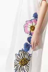 Túnica larga blanca abotonada con estampas de flores en tonos azules y rosados. De calce holgado, cuenta con manga tres cuartos y tablón en la espalda.