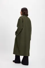 Tapado largo de paño de lana con silueta holgada, corte recto y solapas grandes. Cuenta con cierre frontal y detalles de botones en los puños.