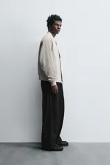 Cazadora bomber ligera de tejido técnico color verde oliva, con cuello, puños y bajo en rib elástico. Presenta cierre frontal de cremallera y bolsillos de vivo en la cadera.