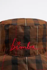 Gorro tipo bucket con estampado escocés en tonos marrón, negro y rojo. Tiene el logo de la marca bordado en rojo en el frente.