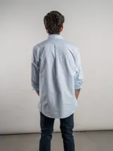 Camisa de corte regular confeccionada en tejido Oxford de algodón, con diseño de rayas verticales finas. Presenta cuello abotonado, cierre frontal con botones y un bolsillo en el pecho.