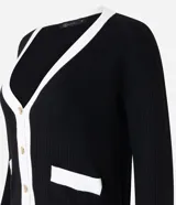 Cardigan de punto blanco con escote en V, botones metalizados, bolsillos falsos, cuello y vista contrastantes en negro, y bajo acanalado.