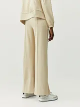 Pantalón recto color beige de tejido Peach-T, suave y elástico, con bolsillos laterales, costura vertical frontal y cordones de ajuste en la cintura.