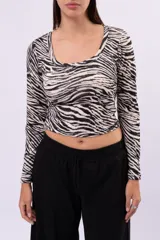 Remera cropped de manga larga con escote redondo, confeccionada en tejido elástico con estampado animal print tipo cebra.