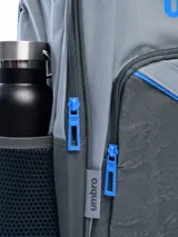 Mochila negra marca Umbro, con logo blanco en el frente y estampado de logos en relieve en la parte inferior. Cuenta con un bolsillo lateral de malla para botella y cierres con tiradores blancos.