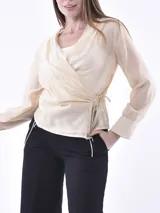 Blusa negra de estilo envolvente con mangas largas, puños anchos y cierre lateral con lazo. Confeccionada en tejido semitransparente.