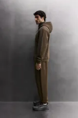 Sudadera con capucha y cierre de cremallera frontal, color negro, confeccionada en tejido técnico compacto de algodón elástico. Presenta cuello subido, bolsillos frontales con cremallera y acabado termofijado, y puños y bajo en rib del mismo tejido.