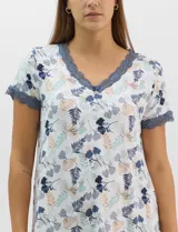 Camisón corto de tejido soft, color blanco con estampado floral y de hojas en tonos azules y marrones. Cuenta con mangas cortas y escote en V con terminaciones de encaje azul en el cuello, las mangas y el ruedo.