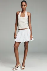 Top de punto negro con cuello halter y escote redondo, decorado con tachas metálicas plateadas distribuidas por toda la prenda.