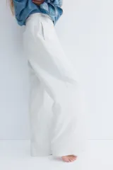 Pantalón de jogging de corte ancho y tiro alto, color gris melange, confeccionado en tejido de felpa con interior cepillado suave. Posee cintura elástica fruncida con cordón de ajuste oculto, bolsillos laterales y un bolsillo trasero abierto.