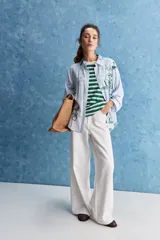 Camisa de calce relajado con cuello clásico, mangas largas con puños elastizados y rayas verticales que aportan un estilo atemporal. Su diseño liviano y versátil cuenta con estampado floral verde sobre fondo de rayas celestes y blancas.